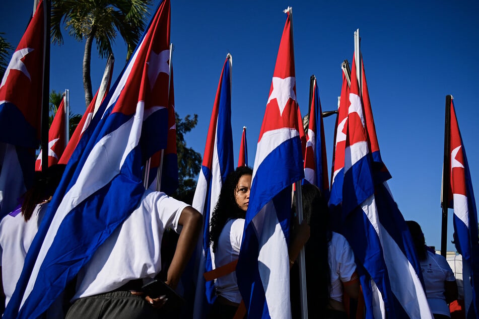 A woman stands amid Cuban flags as she takes part in a demonstration in Havana by women against the sanctions imposed by the US, including the oil embargo in place since January, on April 7, 2026.