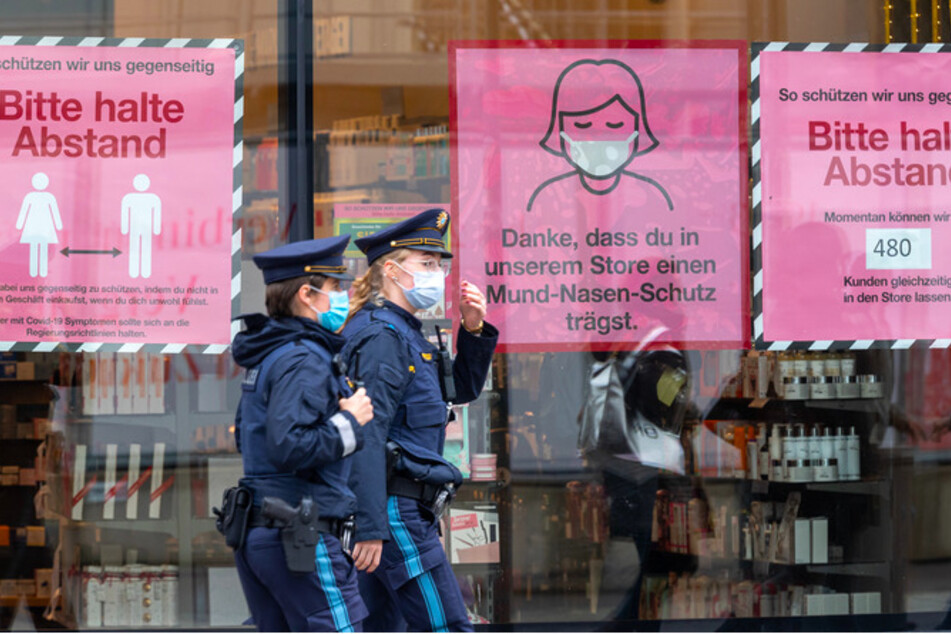 Polizistinnen gehen an einem Schaufenster in der Münchner Innenstadt vorbei.