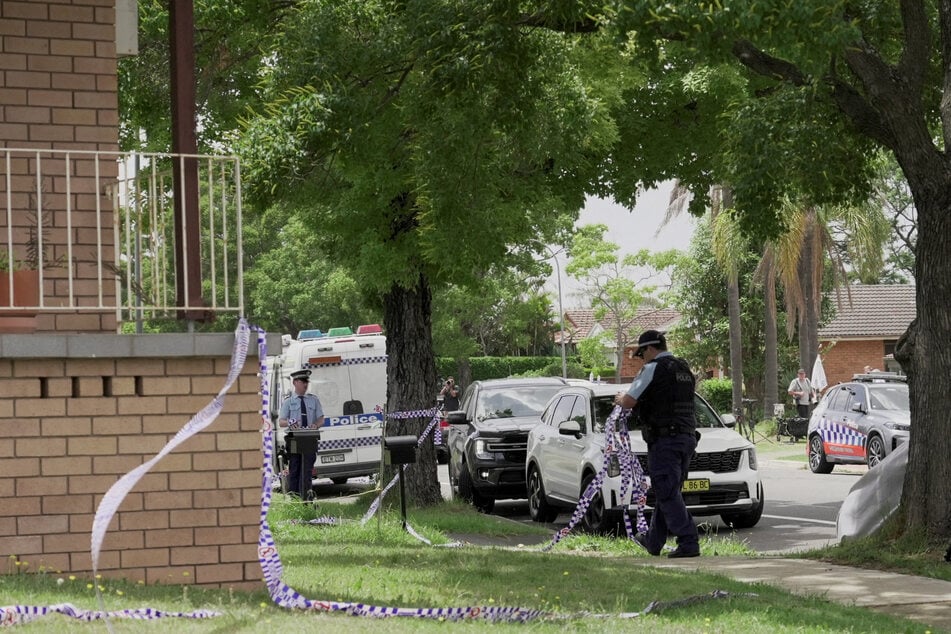 A police officer removes police tape from outside the house of the suspects of a shooting incident on a Jewish holiday celebration at Bondi Beach, in Bonnyrigg, Sydney, Australia, on December 15, 2025.