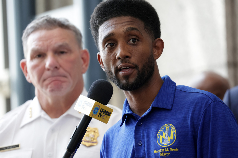 Baltimore Mayor Brandon Scott (r.) speaks at a press conference about the shooting that left two dead and 28 injured.