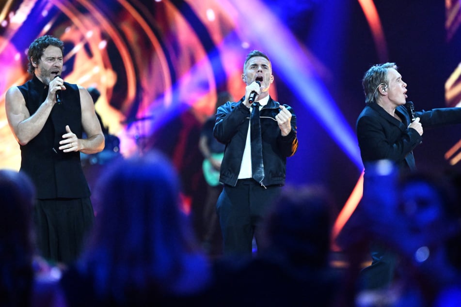 Die Band "Take That" besteht aus Gary Barlow (55, M.), Howard Donald (58, r.) und Mark Owen (54).
