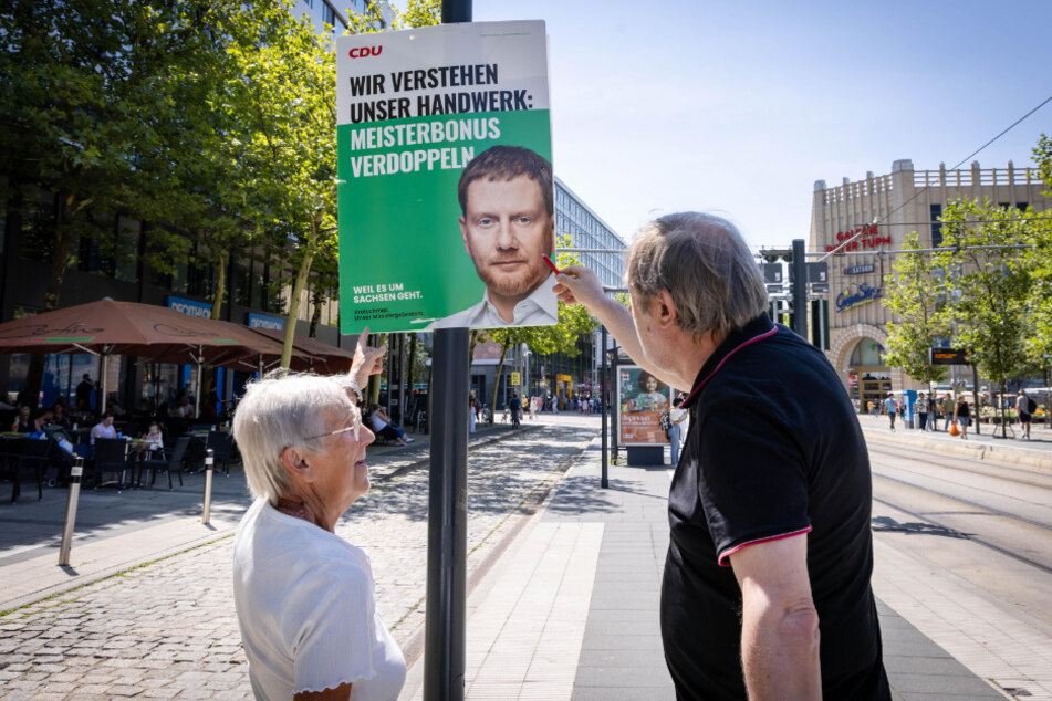 Redakteur Bernd Rippert (r.) sieht sich mit Chemnitzern die Wahlplakate an.