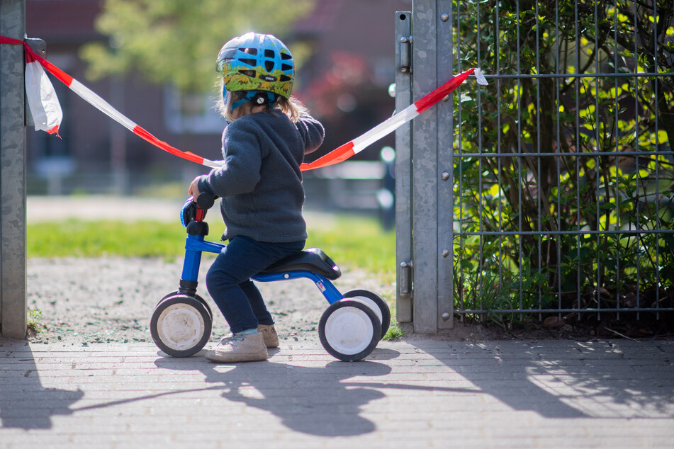 Ein kleines Mädchen steht vor einem abgesperrten Spielplatz. (Symbolbild)