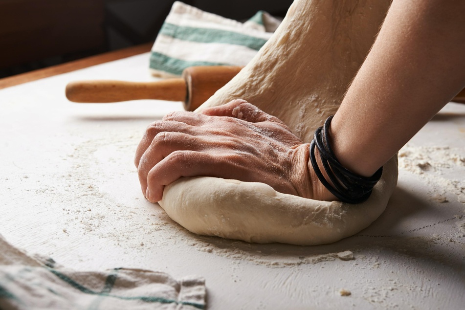 Bevor der Teig als Pizzaboden in Form gebracht wird, muss dieser noch einmal gründlich durchgeknetet werden.