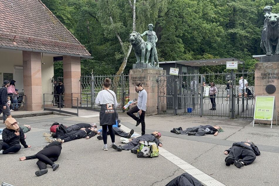Die Aktivisten legten sich aus Protest vor dem Eingang hin. Vier klebten sich fest.