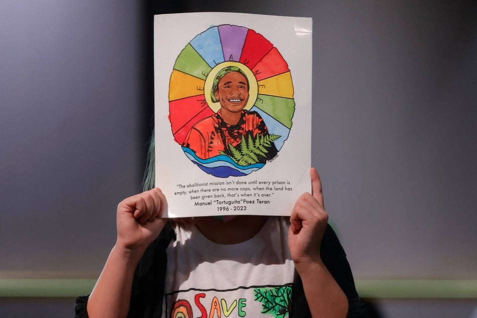 An activist holds up a sign picturing Manuel Esteban Paez Terán (aka Tortuguita), who was killed by law enforcement officers in a January 2023 Stop Cop City raid outside Atlanta, Georgia.