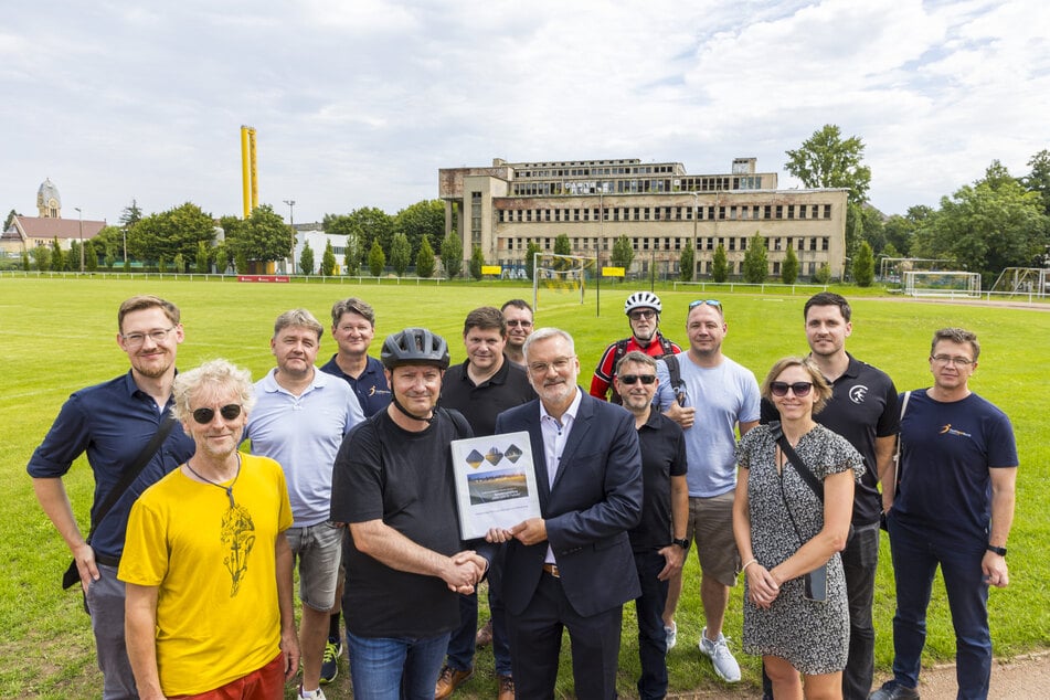 1. FFC Fortuna-Trainer und Vorsitzender des Fördervereins, Prof. Jan Beyer-Westendorf (54, Mitte r.), übergibt feierlich die Planungsunterlagen für die neuen Flutlichtanlagen an Sportbürgermeister Jan Donhauser (56, CDU, Mitte l.).