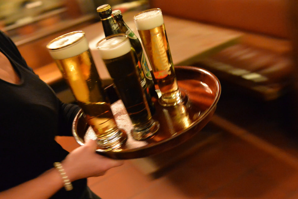 Eine Bedienung trägt in einem Lokal ein Tablett mit Bier. Wer nur einen Corona-Test hat, darf beim 2G-Modell nicht in die Kneipe. (Symbolbild)