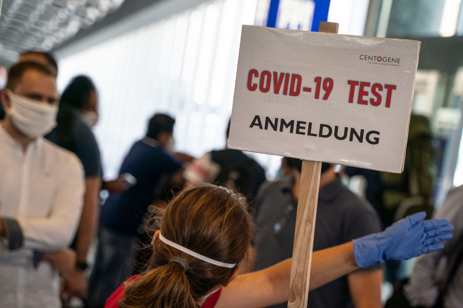 Eine Bedienstete weist in einem Terminal des Frankfurter Flughafens den Weg zur Anmeldung für einen Corona-Test.