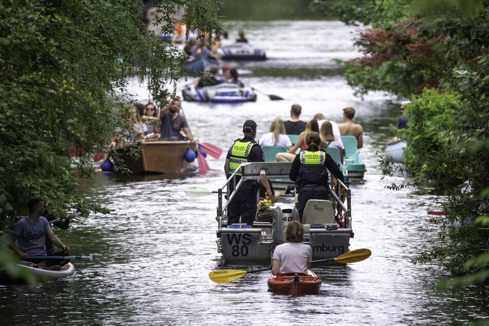 Wasserschutzpolizisten fahren mit einem Motorboot über den Mühlenkampkanal, auf dem viele Freizeitsportler unterwegs sind.