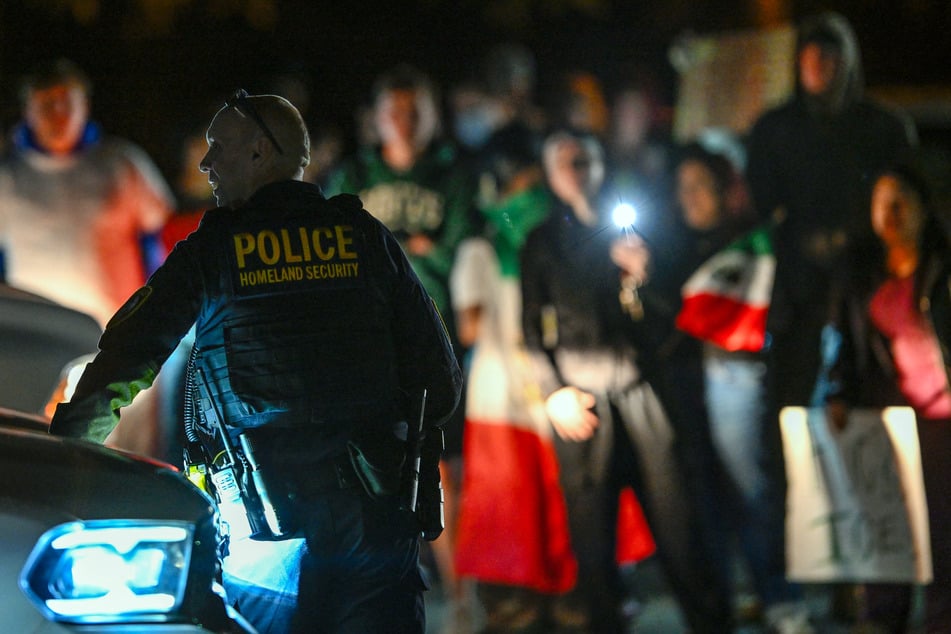 A Department of Homeland Security agent stands guard as protesters demonstrate against federal immigration raids outside the DHS office in Charlotte, North Carolina, on November 16, 2025.
