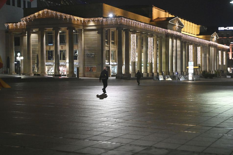 Zwei Menschen laufen während der nächtlichen Ausgangssperre über die verlassene Königstraße in Stuttgart.