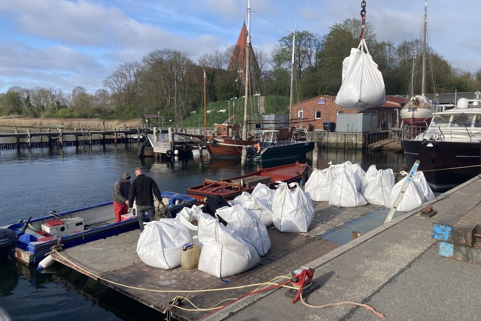 Große Sandsäcke, sogenannte Big Bags, werden im Hafen von Kirchdorf auf Poel per Kran auf einen Ponton abgeladen.