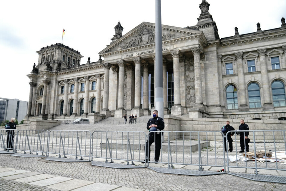 Polizeibeamte sichern hinter Absperrzäunen das Reichstagsgebäude.