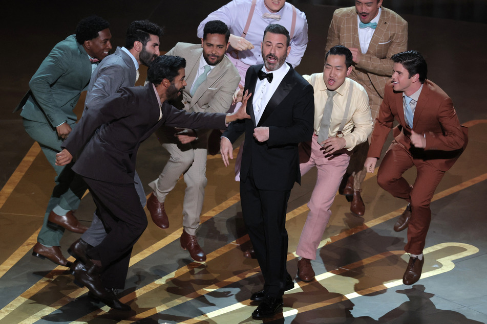 Host Jimmy Kimmel dancing on stage after being parachuted in, in a nod to best picture nominee Top Gun: Maverick.