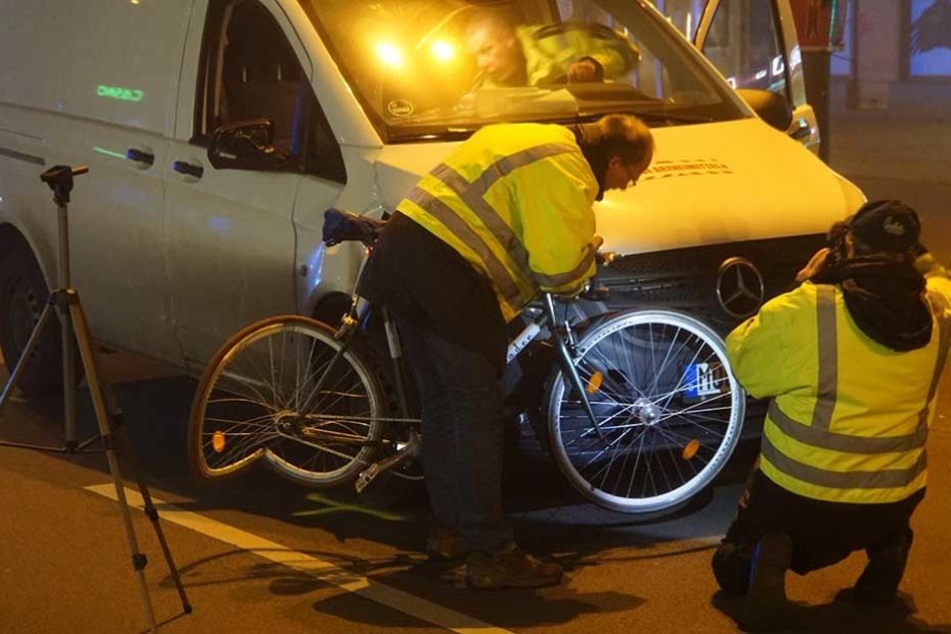 Unfallermittler halten das Fahrrad an die Aufprallstelle des Transporters.