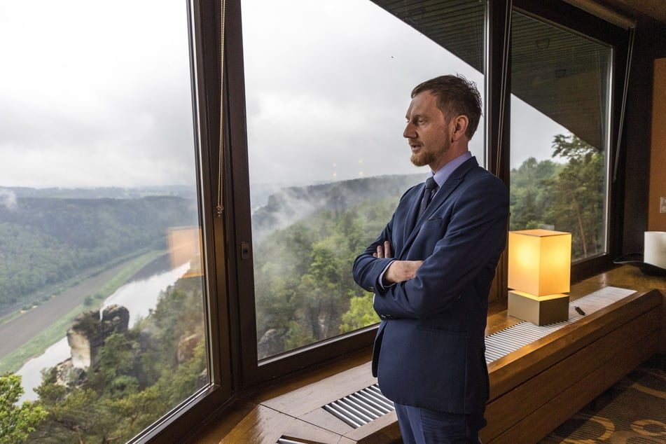 Erst die Arbeit, dann das Vergnügen? Kretschmer schaut bei einem Anzug-Termin fast sehnsüchtig in die Idylle der Sächsischen Schweiz.