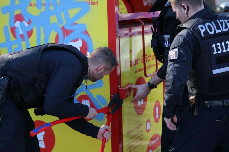 Polizisten brechen die Altkleidercontainer in der Umgebung auf.