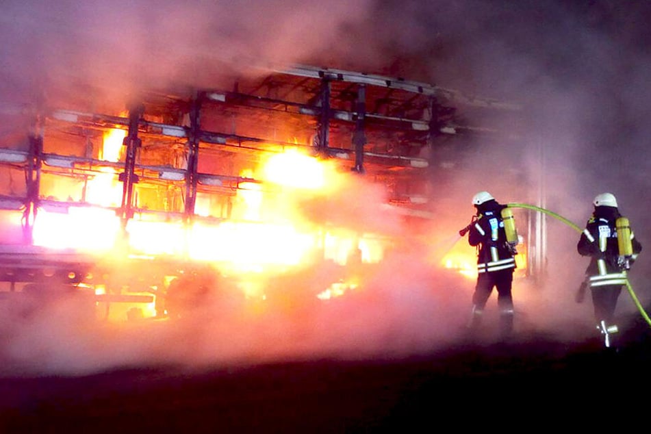 Feuerwehrleute löschen einen brennenden Laster auf der Autobahn.