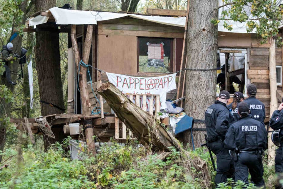 Polizisten stehen in dem Waldstück vor einem von Aktivisten gebauten Baumhaus.