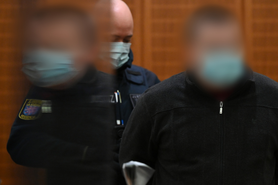 Der Angeklagte (r.) wird zu Beginn eines Mordprozesses von einem Justizbeamten in den Gerichtssaal des Landgerichts Frankfurt geführt. (Archivbild)
