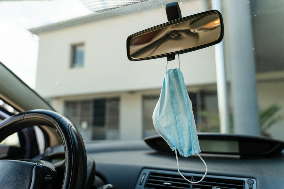 Ein Mund-Nasen-Schutz hängt griffbereit am Rückspiegel eines Autos. In Thüringen ist die 7-Tages-Inzidenz seit Freitag leicht angestiegen.