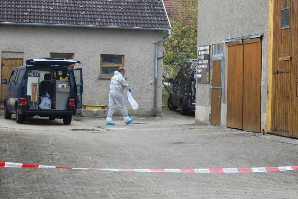 Ermittler der Spurensicherung geht hinter einem Absperrband über den Hof.