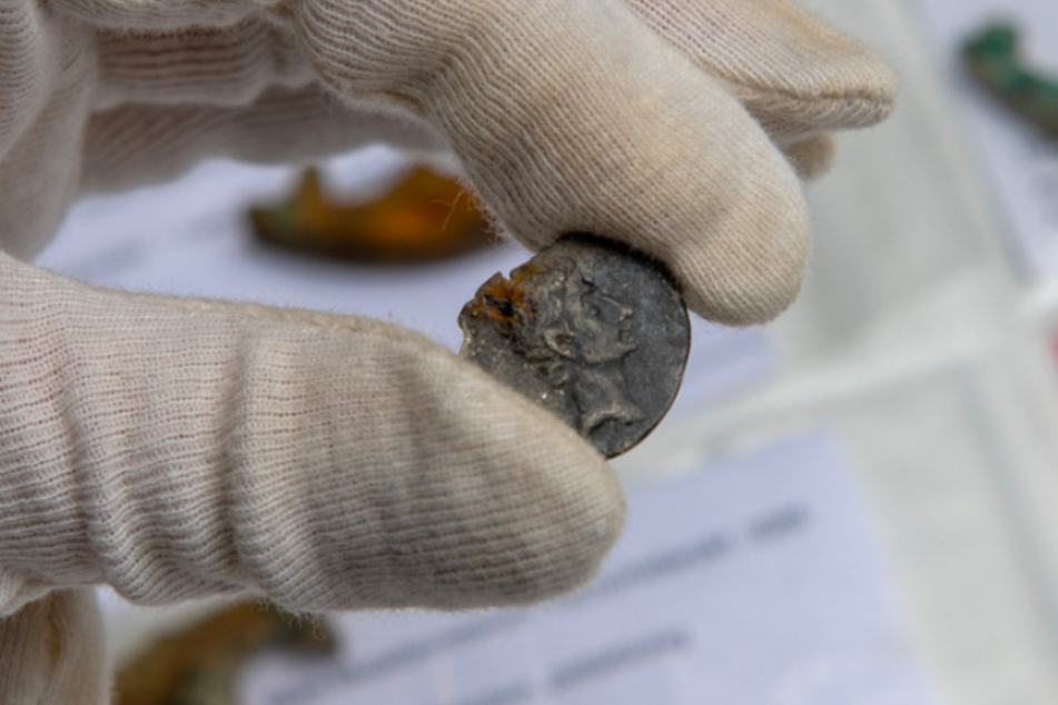 Eine Mitarbeiterin der Stadtarchäologie hält eine gefundene Münze, auf der Kaiser Augustus abgebildet ist.