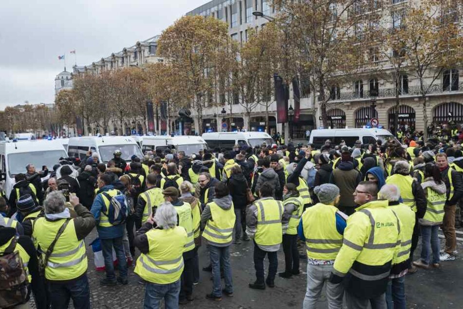 Demonstranten in gelben Warnwesten treffen auf der Champs-Elysees-Allee auf eine Barriere von Polizisten.