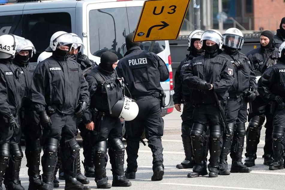 Polizisten entfernen am Baumwall in Hamburg alle losen Gegenstände, die von Demonstranten als Wurfgeschosse verwendet werden könnten.