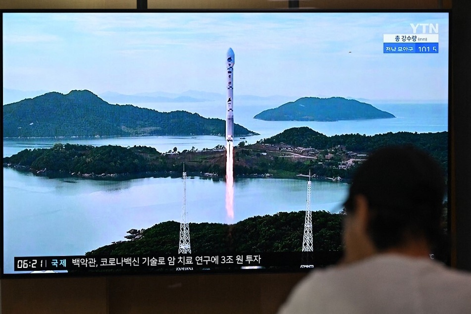 A man at a railway station in Seoul, South Korea, watches a television screen showing footage of a North Korean satellite-carrying rocket launch.