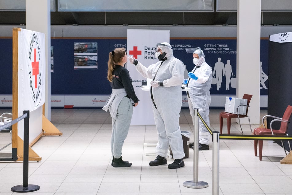 Eine Reisende lässt am Hamburger Flughafen von einem Mitarbeiter des Deutschen Roten Kreuzes (DRK) einen Corona-Test machen.