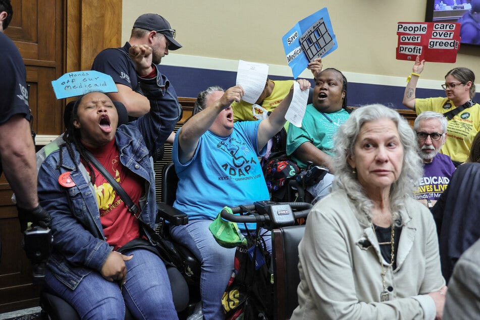 Protesters raise signs and demand no cuts to Medicaid during a House Energy and Commerce Committee hearing on budget reconciliation on May 13, 2025.