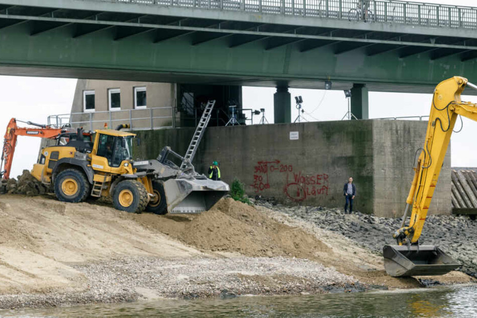 Arbeiter sind dabei den Defekt am Fundament des Elb-Stauwehrs mit Sand abzusichern.