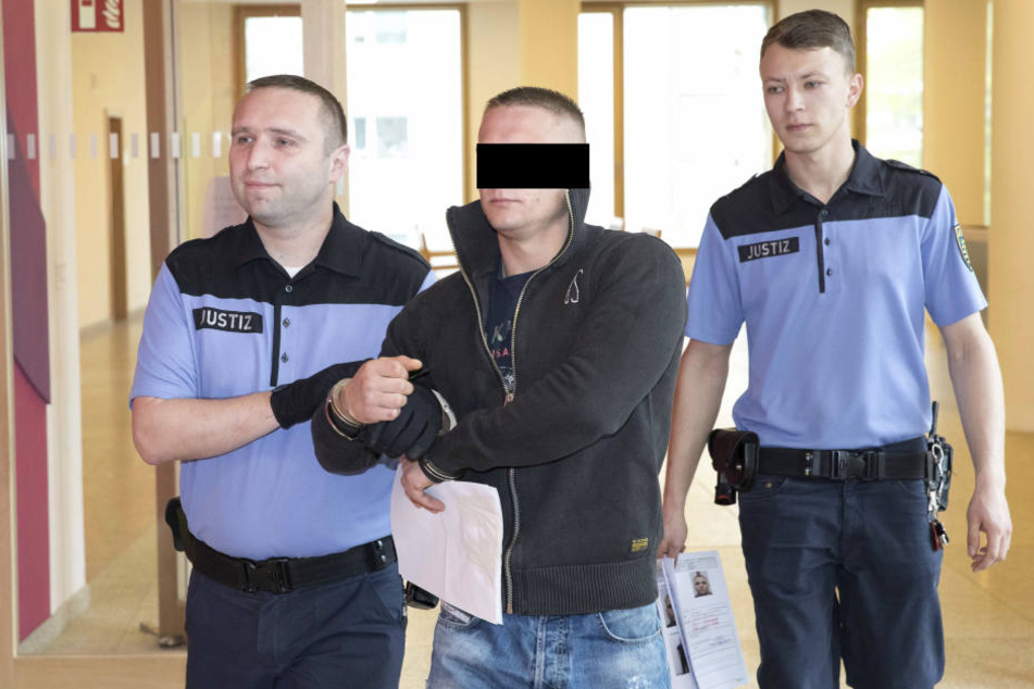 Justizbeamte führen Angeklagten in Handfesseln zum Gerichtssaal.