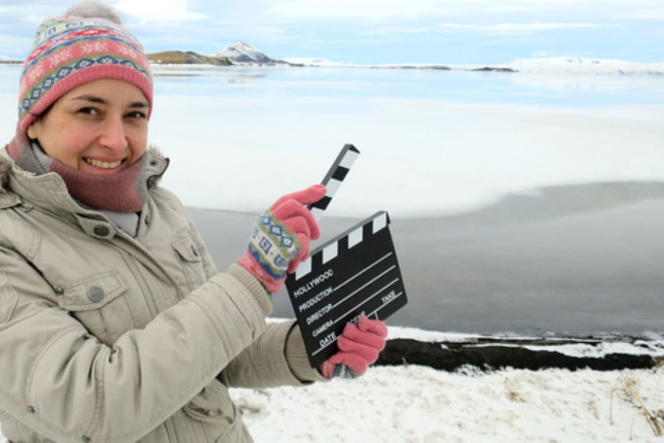 See Mývatn, Island: Bloggerin Andrea David hält eine Filmklappe in die Höhe. Die Hamburgerin bereist Filmkulissen in der ganzen Welt und berichtet auf ihrem Blog und ihrem Instagram-Feed darüber.