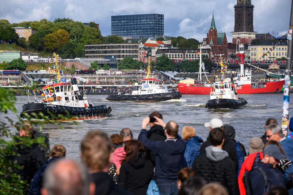 Die Besucher beobachten die Schlepper, die auf der Elbe im Rahmen des "Schlepperballett" Pirouetten drehen.