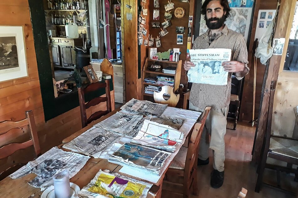 Thimotee Mottin, Leiter des Café-Restaurants Cabane du Cerro, hält eine Ausgabe einer Zeitung in der Hand, die sich wahrscheinlich an Bord der Boeing 707 "Kangchenjunga" der Air India befand.