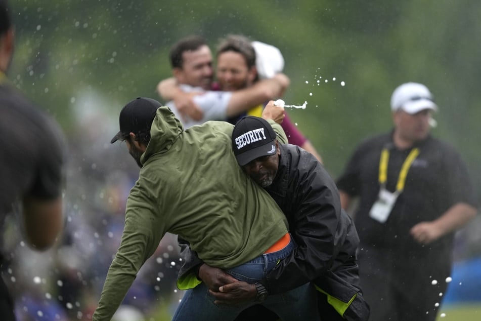 Adam Hadwin (35, v.l.) wird mit einer Champagnerflasche in der Hand von einem Sicherheitsmann getackelt. Im Hintergrund gut zu sehen: Nick Taylor (35, h.l.), der gerade seinen Turniersieg feiert.