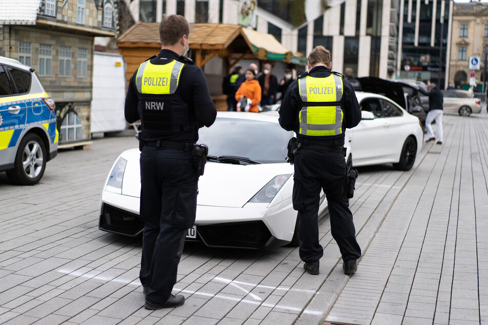 Zwei Polizisten überprüfen auf dem Corneliusplatz während einer Polizeikontrolle die Papiere eines Sportwagen-Fahrers.