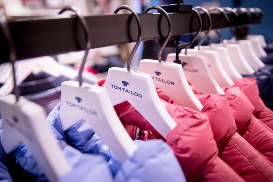 Jacken der Marke Tom Tailor hängen auf Kleiderbügeln in einem Geschäft.
