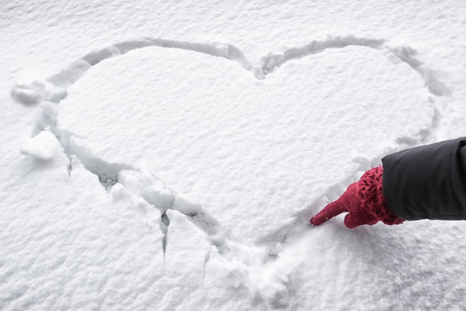 Eine Frau malt ein Herz in den Schnee: Auch beheizbare Handschuhe sind mittlerweile voll im Trend.