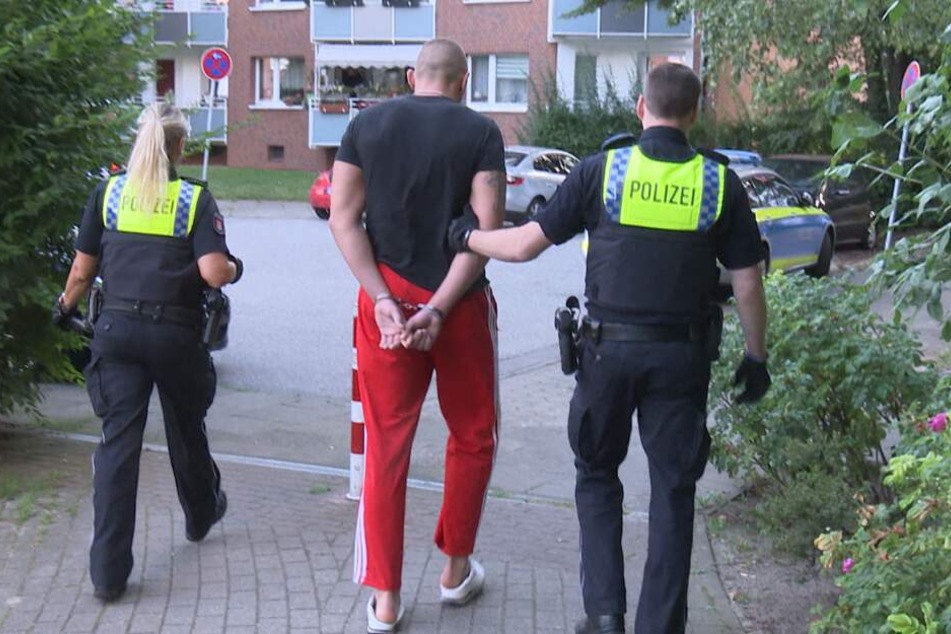 Beamte führen einen der Tatverdächtigen ab.