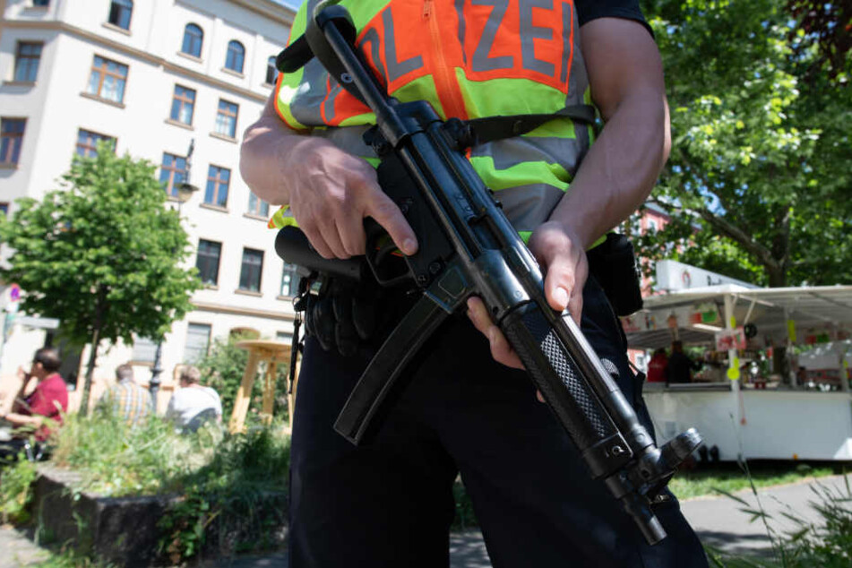 Ein Polizist steht mit der Waffe im Anschlag an der Wegstrecke beim Umzug beim Karneval derKulturen.