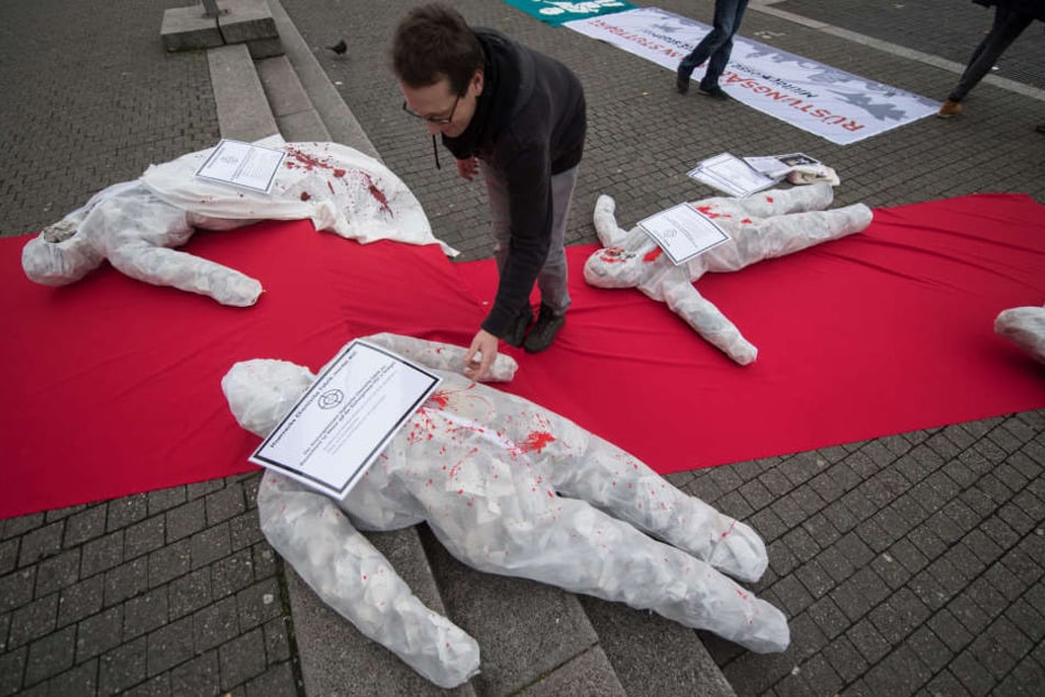 Ein Rüstungsgegner legt vor dem Rathaus bei einer Kundgebung von Rüstungsgegnern gegen die Militärmesse ITEC ein Plakat auf ein symbolisches Kriegsopfer.