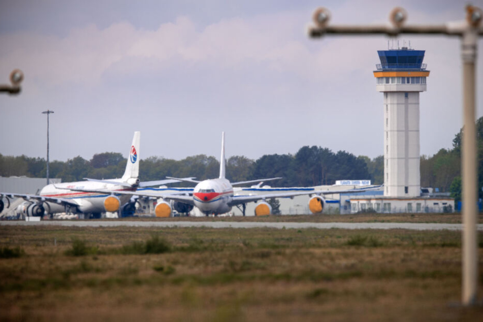 Zwei Airbus-Flugzeuge einer chinesischen Fluggesellschaft stehen auf einer Parkposition vor dem Tower des Airports.