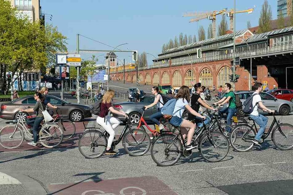 Fahrradfahrer und Autos befahren in Berlin an der Oberbaumbrücke die Kreuzung Mühlenstraße und Warschauer Straße.