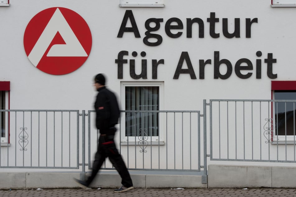 Ein Mann geht an dem Logo der Agentur für Arbeit vorbei. (Symbolbild)