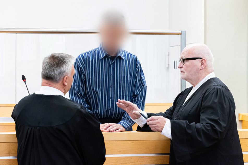 Der Angeklagte (M.) mit seinen Anwälten vor Prozessbeginn am Landgericht Hannover.
