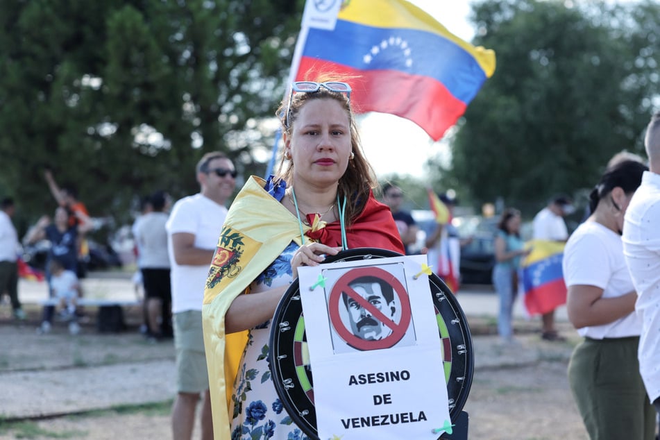 A supporter holds a sign branding Nicolas Maduro the "murderer of Venezuela" at Madrid's Torrejon de Ardoz military airport on September 8, 2024.